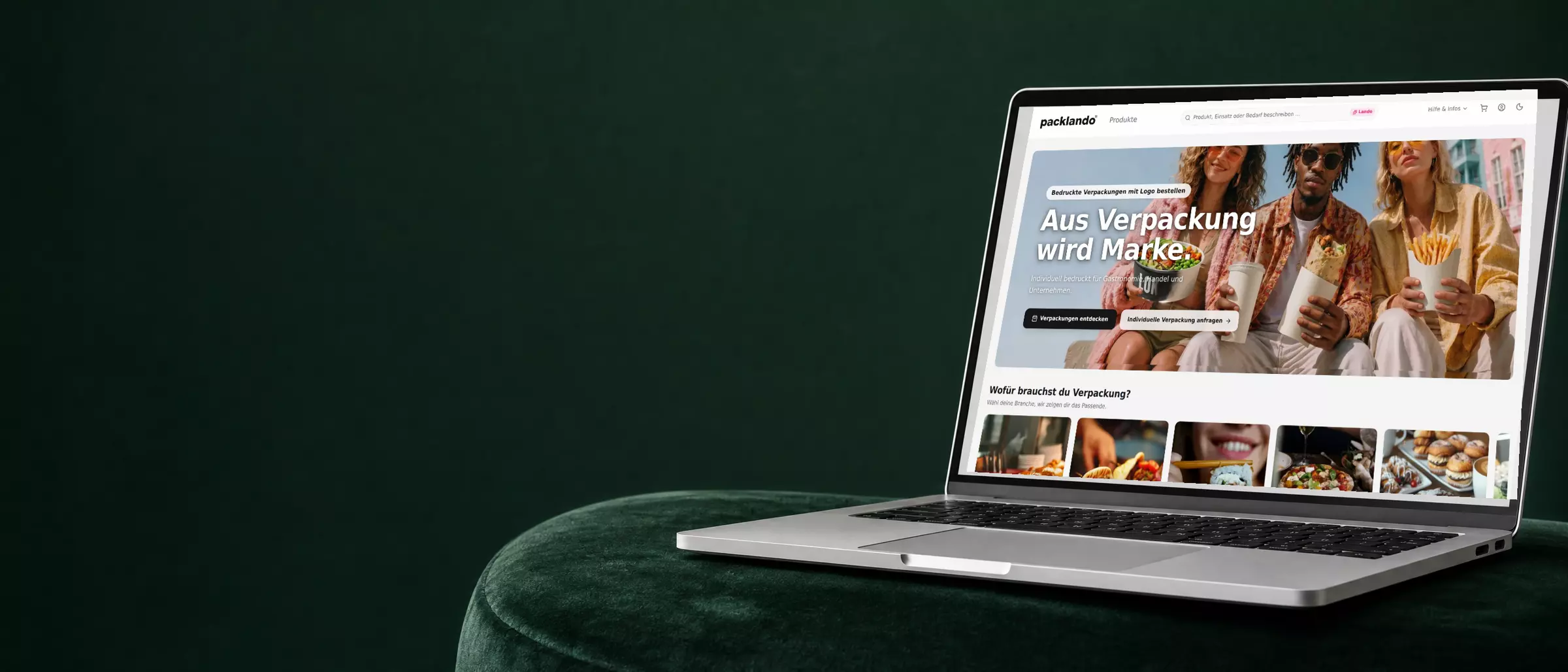 Packlando-Onlineshop auf einem Laptop auf einem grünen Samtsofa vor grüner Wand